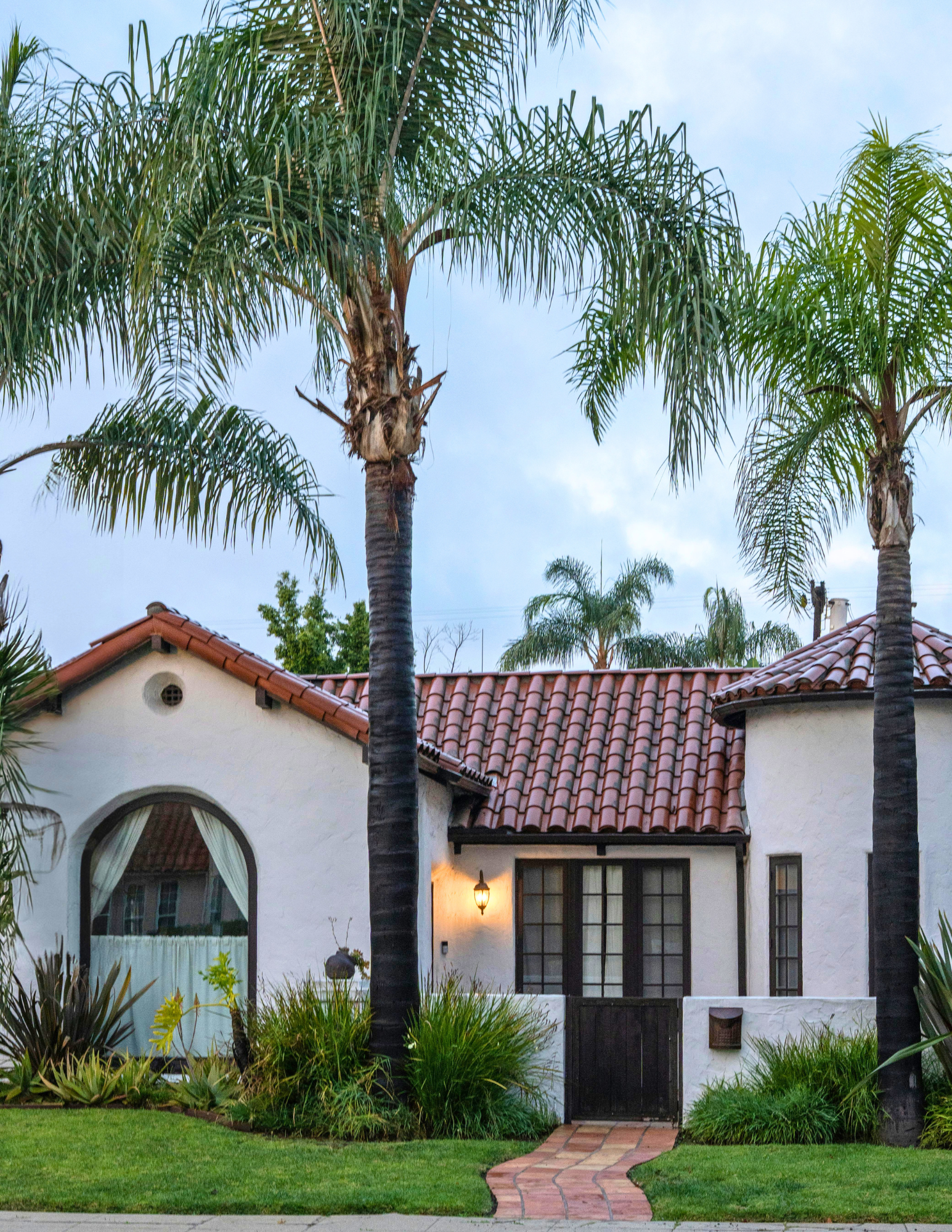 Spanish Mission Revival home with red clay tile roof and palm trees